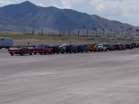 1972 Ford Ranchero - A line of cars, including a red 1972 Ford Ranchero convertible, are parked outdoors with mountains in the distance.