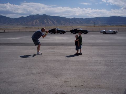1972 Ford Ranchero - A man photographs two children in front of a line of classic cars with mountains in the distance.