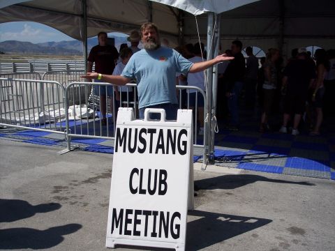 1972 Ford Ranchero - A man stands before a sign announcing a Mustang Club Meeting, with a crowd visible in the background.