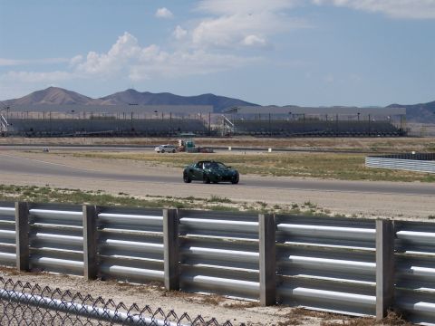 1972 Ford Ranchero - A green convertible is on the racetrack, with a white car in the distance and grandstands behind them.