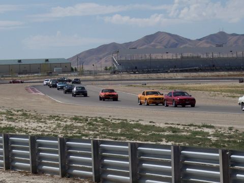 1972 Ford Ranchero - Multiple vehicles compete on a race track under a clear sky with distant mountains.