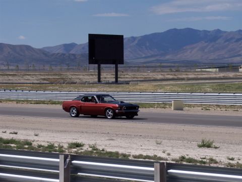 1972 Ford Ranchero - A classic muscle car cruises down the asphalt track under a clear blue sky.