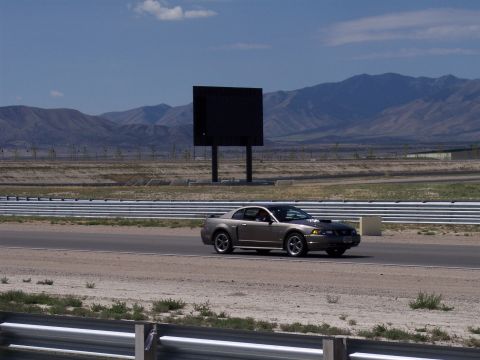 1972 Ford Ranchero - A 2000 Ford Mustang coupe drives on a race track with a large blank screen and mountains visible.