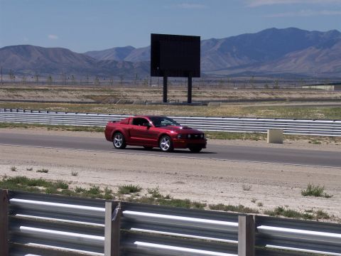1972 Ford Ranchero - A red coupe drives on a paved track with mountains in the background.