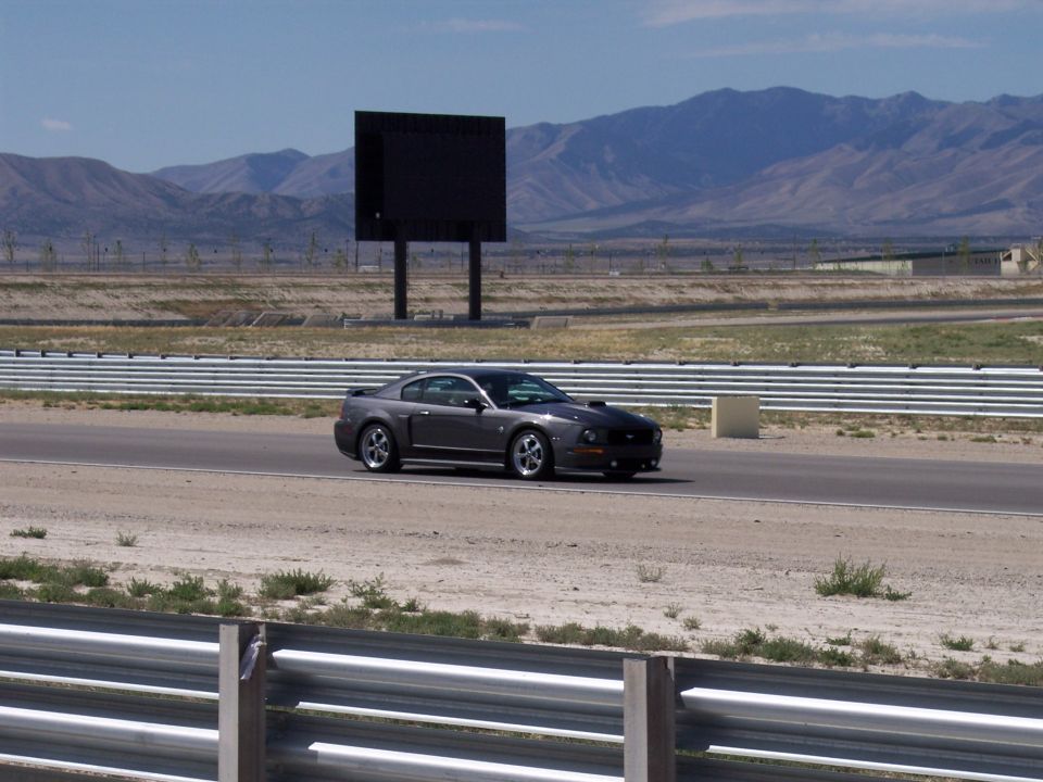 Gray Mustang coupe on a racetrack with mountains behind