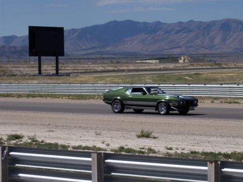 1972 Ford Ranchero - A green 1971 Ford Mustang Mach 1 is driving on a racetrack with a large black screen in the background.