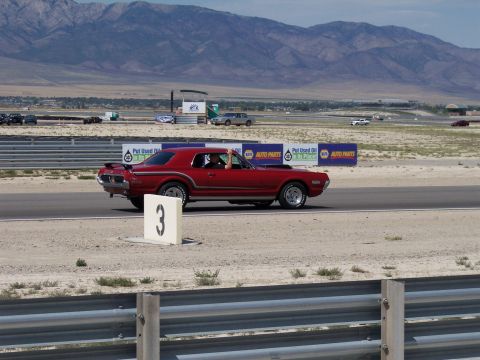 1972 Ford Ranchero - A red 1970 Mercury Cougar Eliminator drives on a racetrack with mountains in the background.