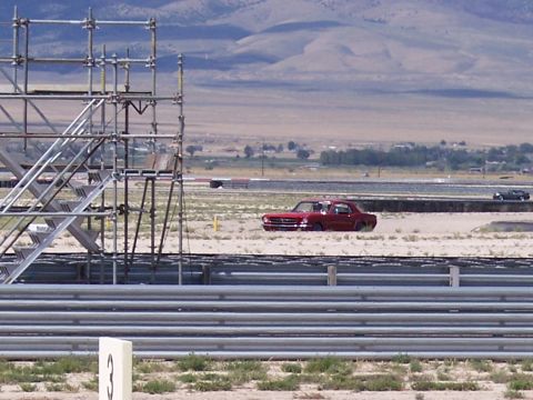 1972 Ford Ranchero - A red 1965 Ford Ranchero is seen on a dirt track, with scaffolding in the foreground and mountains in the background.