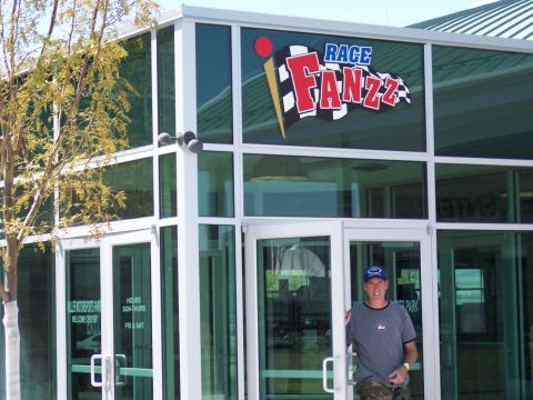 1972 Ford Ranchero - Man stands at the entrance of a building with 'RACE FANZZ' signage above the glass doors.