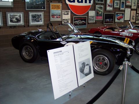 1972 Ford Ranchero - A black 1965 Shelby Cobra 427 S/C with yellow stripes is displayed next to a red car.