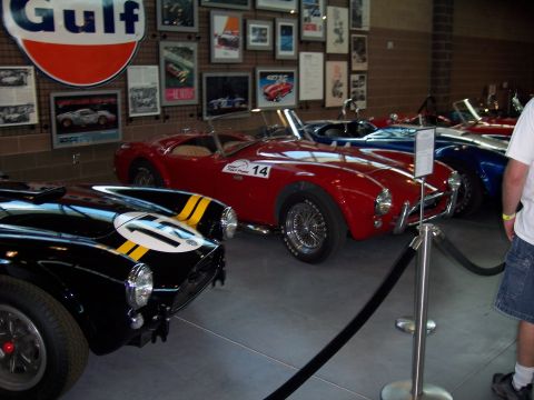 1972 Ford Ranchero - A collection of vintage sports cars are on display in a museum-like setting with memorabilia on the walls.