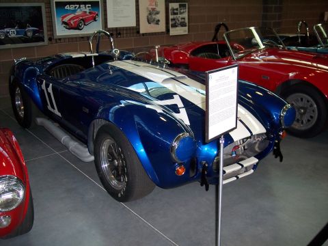 1972 Ford Ranchero - A blue and white race car with side pipes is displayed next to other vehicles, with informational signs on display.