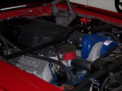 1972 Ford Ranchero - Close-up of a red vehicle's engine bay, showing a blue supercharger and "COBRA POWERED BY FORD" valve covers.