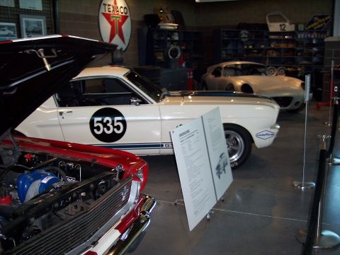 1972 Ford Ranchero - A white 1965 Shelby GT350 race car, number 535, is displayed next to a red car and another vehicle in the background.
