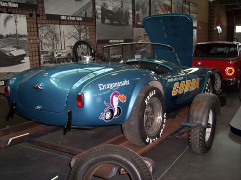 1972 Ford Ranchero - Shelby Cobra Dragonsnake race car on display, with a red car in the background.