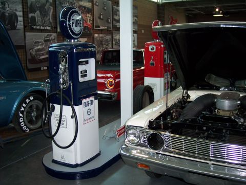 1972 Ford Ranchero - A collection of vintage gas pumps and classic cars are displayed indoors.