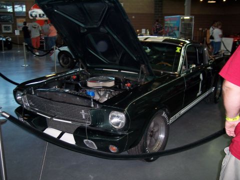 1972 Ford Ranchero - A dark green 1965 Ford Mustang is displayed with its hood open, revealing the engine bay.
