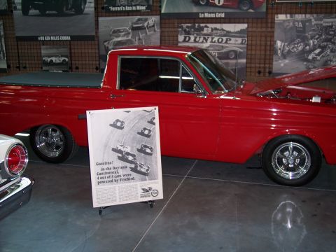 1972 Ford Ranchero - A red pickup truck is displayed indoors with racing-themed posters in the background.