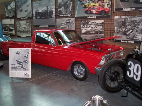 1972 Ford Ranchero - A red pickup truck is displayed indoors with racing memorabilia on the walls.