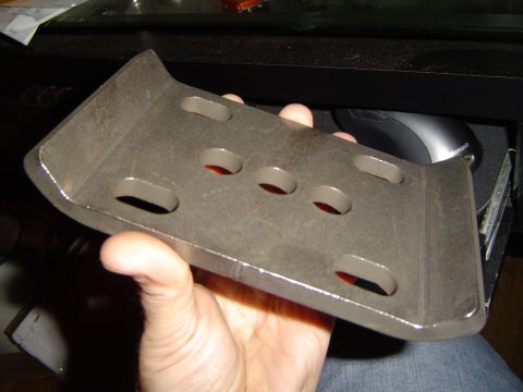 1978 Ford Bronco - A metal bracket with several holes is held in a hand, with a computer mouse visible in the background.