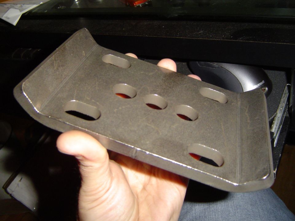 Metal bracket with multiple oval and circular holes, held by a hand