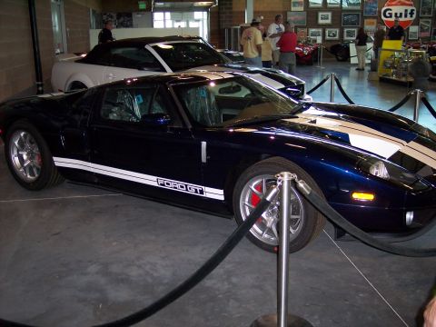 1972 Ford Ranchero - A dark blue Ford GT with white stripes is displayed indoors, with another car behind it.