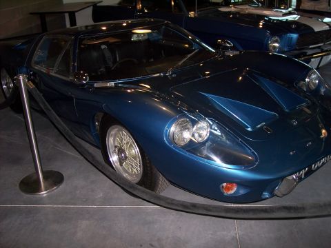 1972 Ford Ranchero - A blue sports car with distinctive hood scoops and wire wheels is displayed next to another blue vehicle.