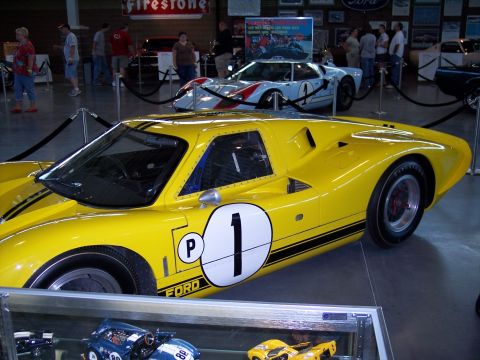 1972 Ford Ranchero - A yellow Ford GT40 race car is displayed indoors with other vehicles and memorabilia.