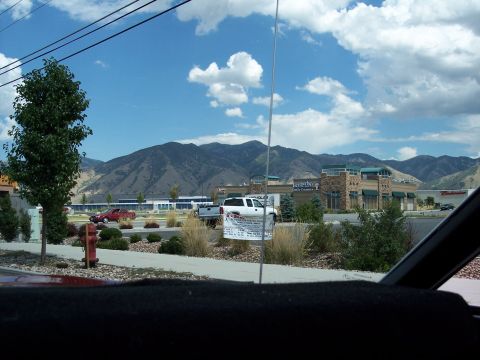 1972 Ford Ranchero - Mountains loom over a commercial area with several vehicles parked in the lot.