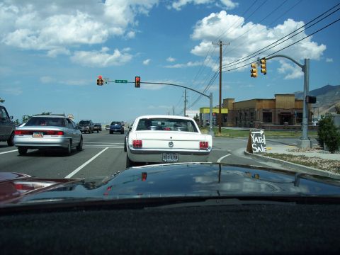 1972 Ford Ranchero - A white coupe is stopped at a traffic light on a sunny day, with a 'Yard Sale' sign visible on the right.