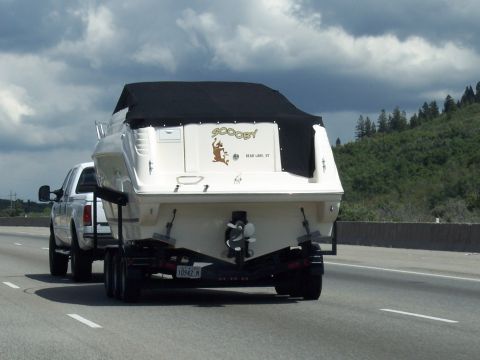 1972 Ford Ranchero - A white boat with the name "Scooby" is towed by a white pickup truck on a highway.