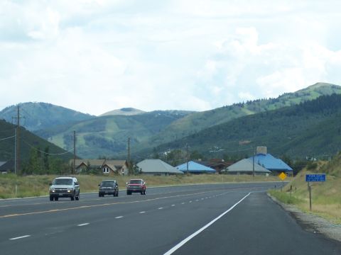 1972 Ford Ranchero - A highway passes through a valley with mountains and houses under a cloudy sky.