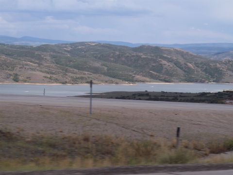 1972 Ford Ranchero - A scenic view of a lake and rolling hills under a partly cloudy sky, likely taken from a moving vehicle.