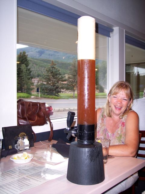 1972 Ford Ranchero - A woman laughs at a table with a tall beer dispenser, with a scenic mountain view outside.
