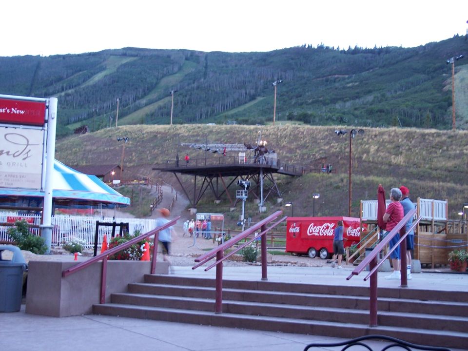 Ski resort base area in summer with steps, Coca-Cola trailer and chairlift platform on a green hillside