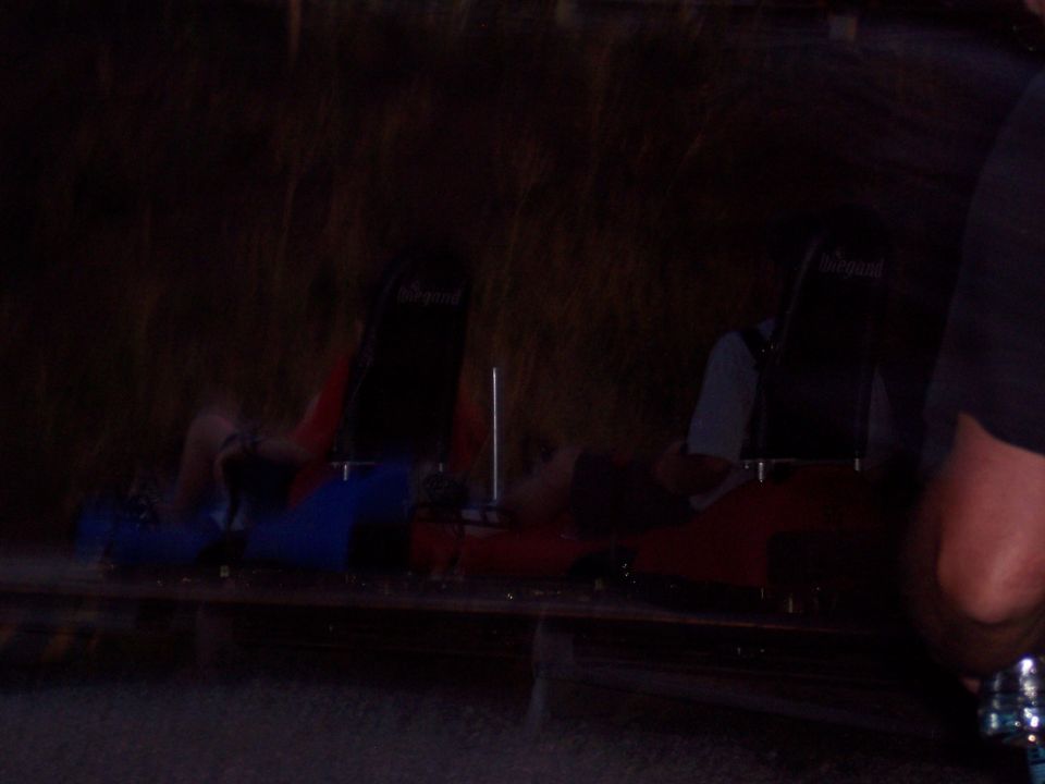 Dark photo of Wiegand ride cars with red and blue bodies and seated riders