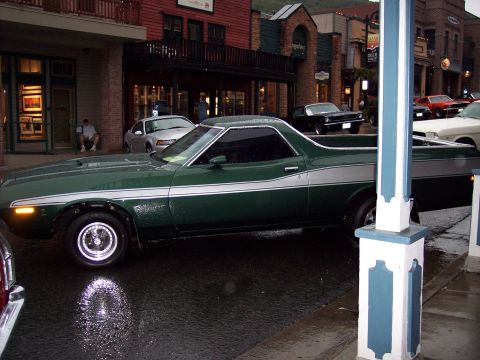 1972 Ford Ranchero - 1972 Ford Ranchero parked on a wet street in a town with historic buildings.