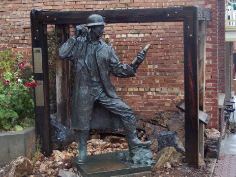 1972 Ford Ranchero - A statue depicting a miner stands in front of a brick building, surrounded by rocks.