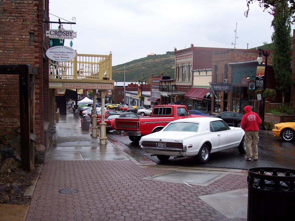 Red vintage car-pickup parked on wet brick street among other classic cars