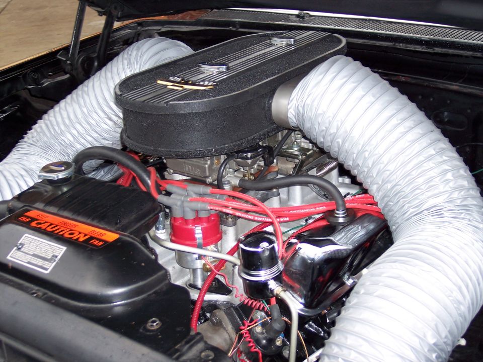 V8 engine bay with oval air cleaner, red distributor wires, and white flex ducting
