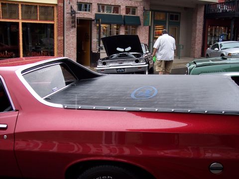 1972 Ford Ranchero - A red pickup truck is parked next to other vehicles on a street.