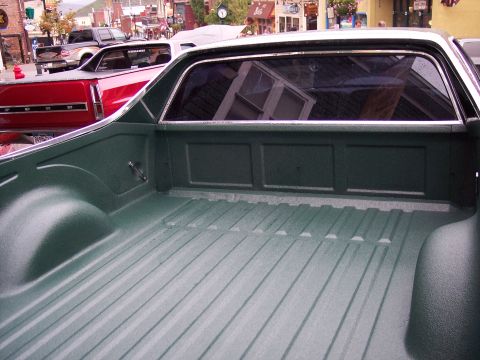 1972 Ford Ranchero - The ribbed bed of a green 1972 Ford Ranchero is shown from the rear, with another vehicle visible in the background.