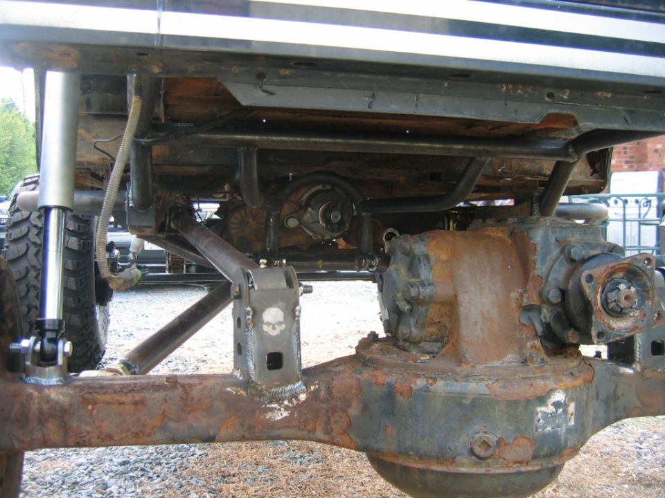 Undercarriage of modified off-road vehicle showing differential and suspension components with skull emblem