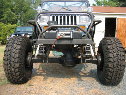 1992 Ford Mustang - A heavily modified Jeep Wrangler is parked in front of a building, with another Jeep visible in the background.