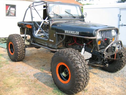1992 Ford Mustang - Modified black Jeep Wrangler with prominent off-road tires and a full roll cage visible.
