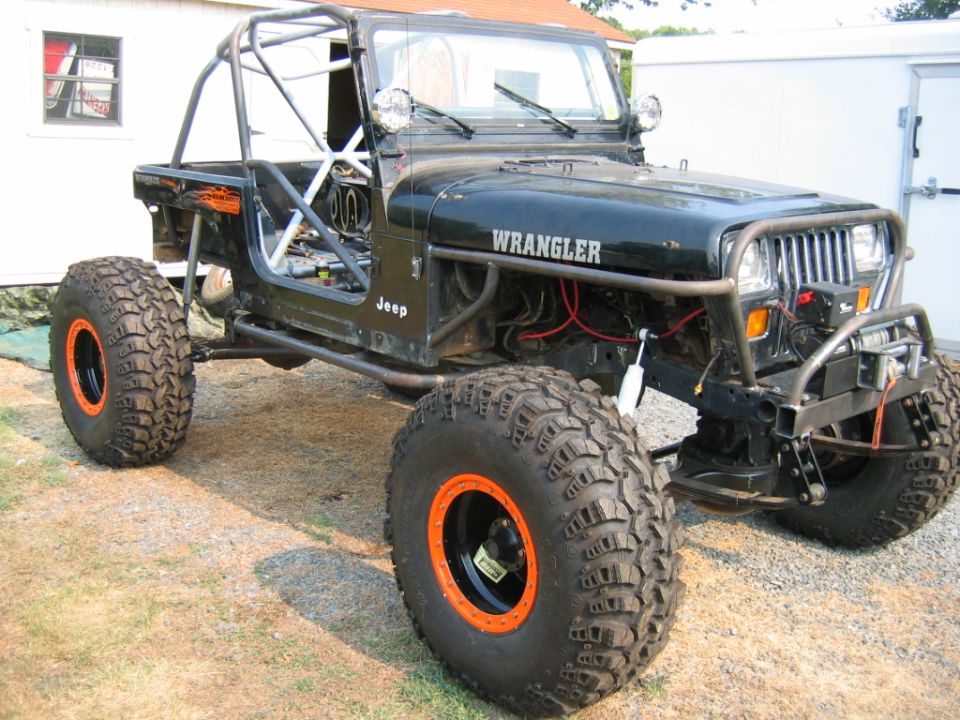 Black Jeep Wrangler with large off-road tires and custom roll cage