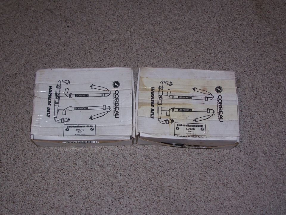 Two boxed Corbeau 44001B four-point black harness belts on carpet