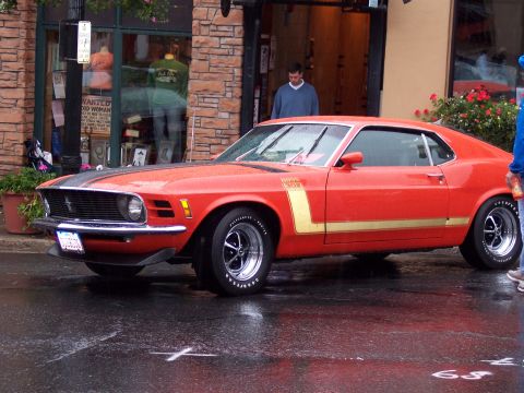 1972 Ford Ranchero - This 1970 Ford Mustang Boss 302 features a distinctive gold stripe and is captured on a wet street, possibly after rain.