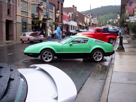 1972 Ford Ranchero - A street scene with multiple cars, including a green sports car and a red pickup truck.