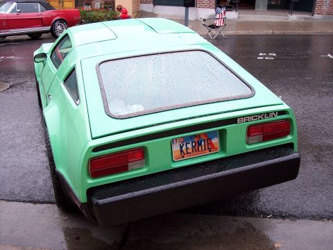 1972 Ford Ranchero - A green Bricklin SV-1 is seen from the rear on a wet street, with a red Ford Mustang nearby.